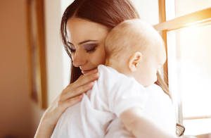 Cute little baby in the arms of her mother in a living room.